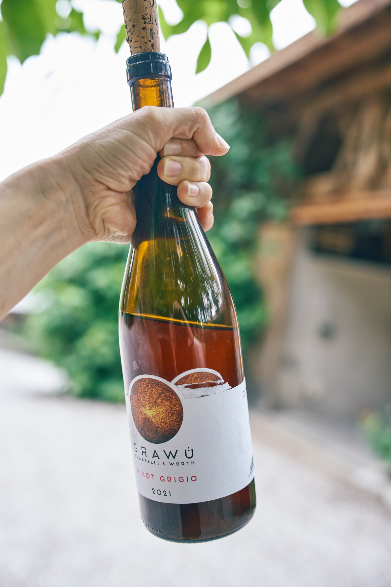 Eine Hand hält eine Flasche GRAWÜ Pinot Grigio 2021 im Tageslicht